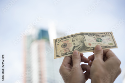 Hand holding banknote dollar and showing money. There is a building background.