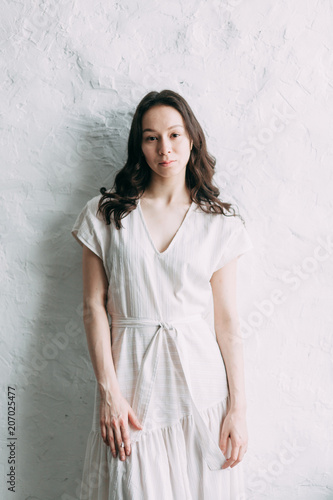 Cute girl in white airy dress, in the loft Studio. Portrait photo shoot with natural light. Beautiful look and fine art in photo processing