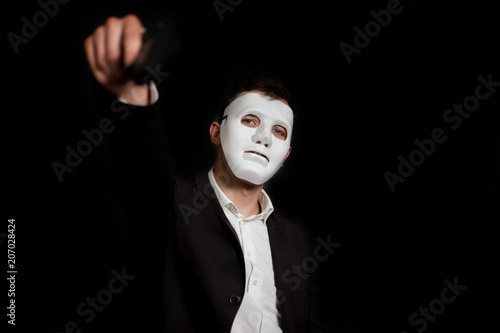 A man in a white mask on a black background, threatens with a gun