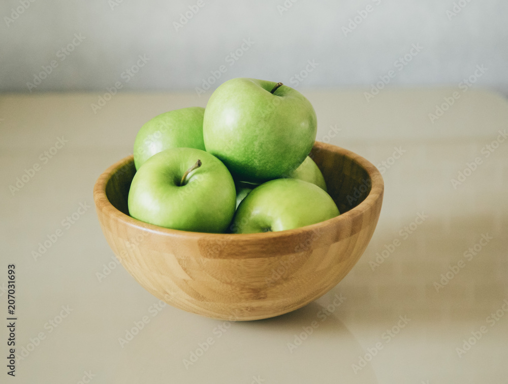 green fresh apples are in a wooden bowl in the kitchen green fresh apples are in a wooden bowl in the kitchen