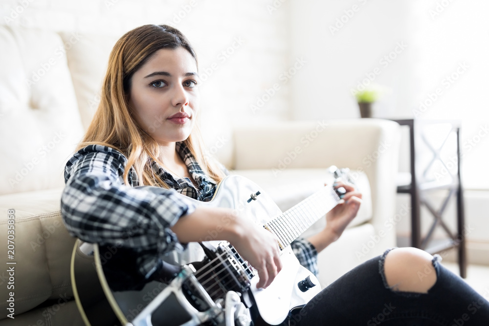Beautiful girl playing guitar at home