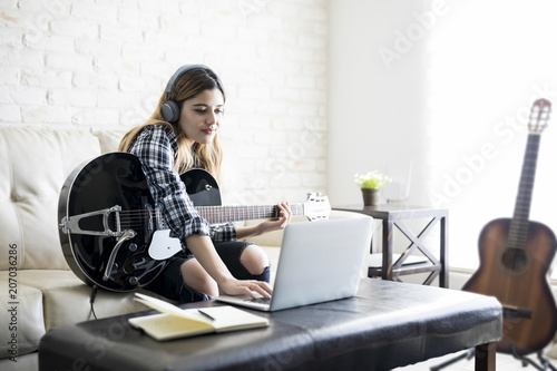 Musician composing a song with laptop and guitar