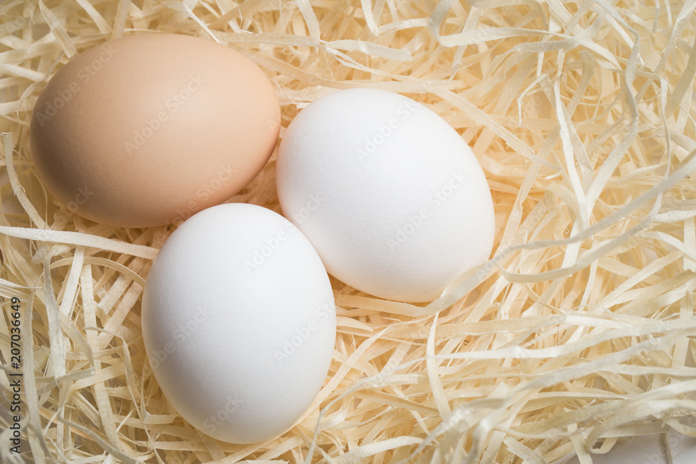 Three chicken eggs lie in a nest of straw, shot close-up Three chicken eggs lie in a nest of straw, shot close-up