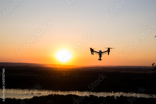 silhouette of drone, quadrocopter with photo camera flying in the sky.