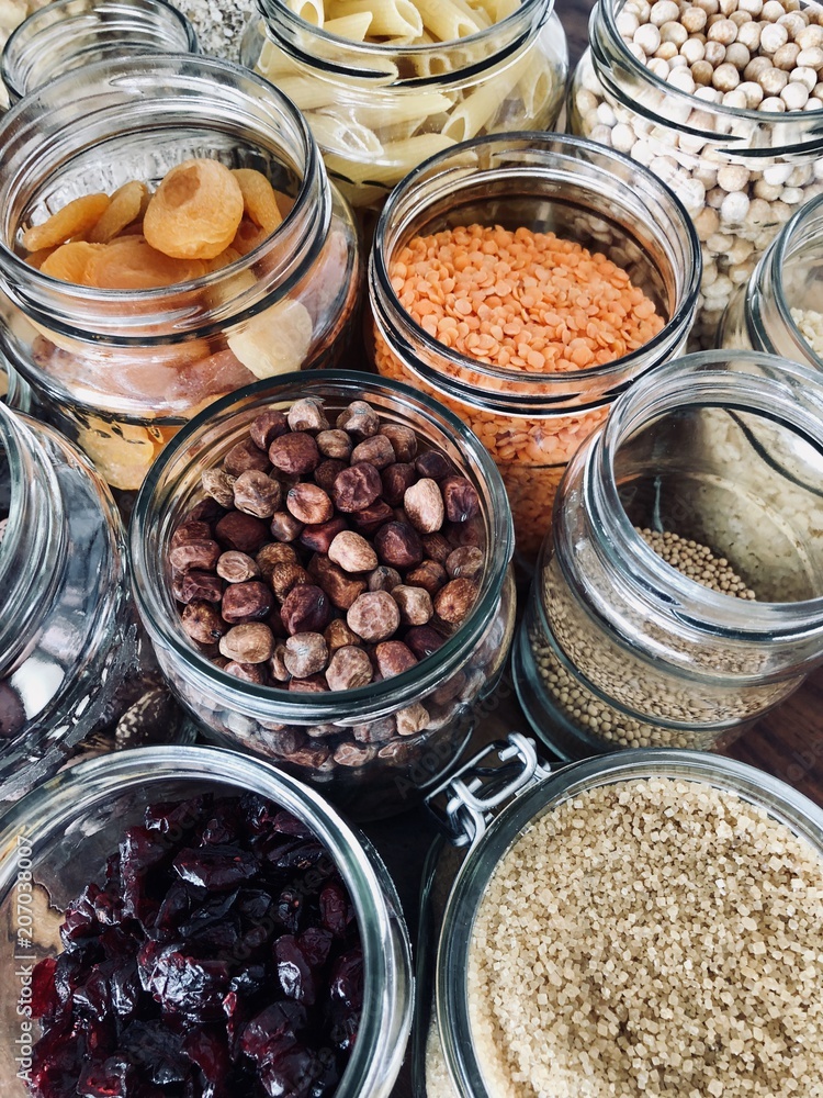 Healthy cereals and fruits in glass jars and reusable bags with fresh basil on wooden background in daylight Healthy cereals and fruits in glass jars and reusable bags with fresh basil on wooden background in daylight