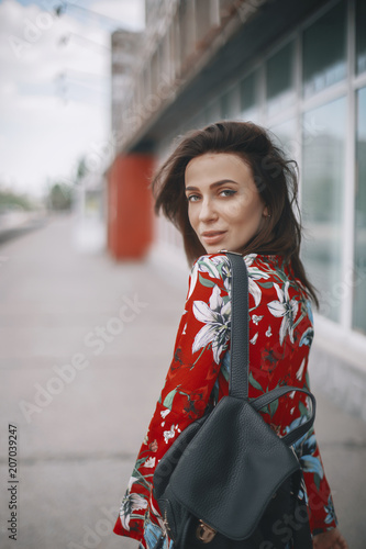 the woman is walking by the window. girl with short hair, brunette walking in red overalls with tropical ornament. © zvkate