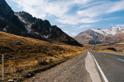 road at the foot of high mountains, autumn nature and cold blue sky