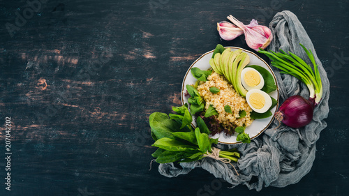 Bulgur with avocado, spinach and boiled egg. On a wooden background. Top view. Copy space.