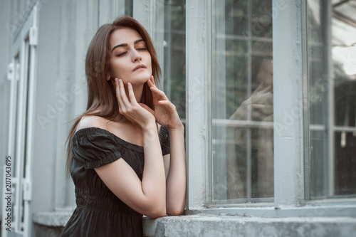 Sensual brunette woman wearing dress with naked shoulders, posing at the greenhouse. Space for text © vpavlyuk