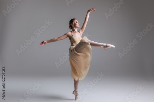 Dance to inspire! Full length side view of the classical ballet dancer performing ballet movements on the isolated background.