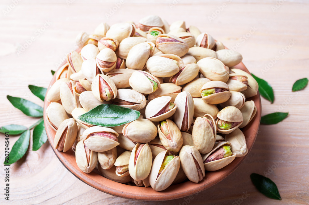 Pistachios nuts in bowl. Pistachio with leaves. Healthy food, snacks, vegetarian food Pistachios nuts in bowl. Pistachio with leaves. Healthy food, snacks, vegetarian food