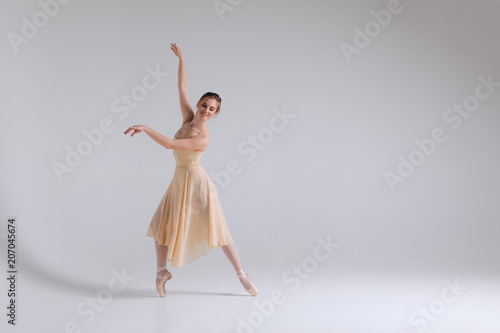 Dialogue of dance! Full length picture of the smiling delicate full of tenderness ballerina standing in pointe position.