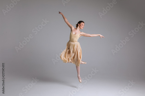 As light as a feather! Young attractive graceful gentle ballerina dancing in the art performance on the isolated background.