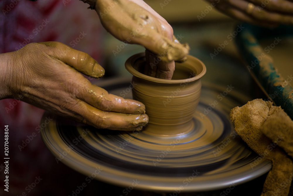 Sculpts in clay pot closeup. Modeling clay close-up. Caucasian man making vessel daytime of white clay in fast moving circle. Art, creativity. Ukraine, cultural traditions. Hobbies