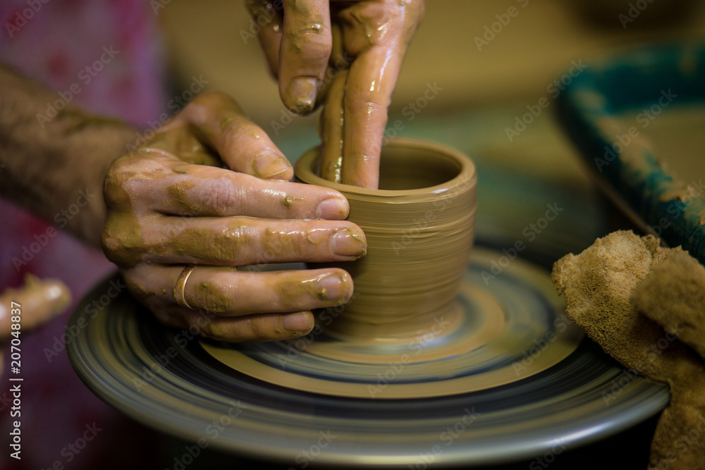 Sculpts in clay pot closeup. Modeling clay close-up. Caucasian man making vessel daytime of white clay in fast moving circle. Art, creativity. Ukraine, cultural traditions. Hobbies Sculpts in clay pot closeup. Modeling clay close-up. Caucasian man making vessel daytime of white clay in fast moving circle. Art, creativity. Ukraine, cultural traditions. Hobbies