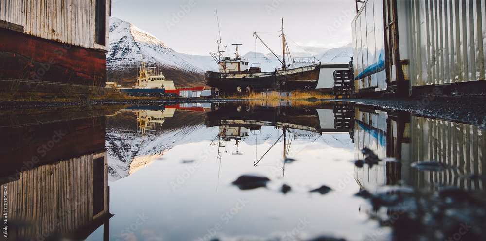 Reflection in a crystalline puddle of aground and old boat.