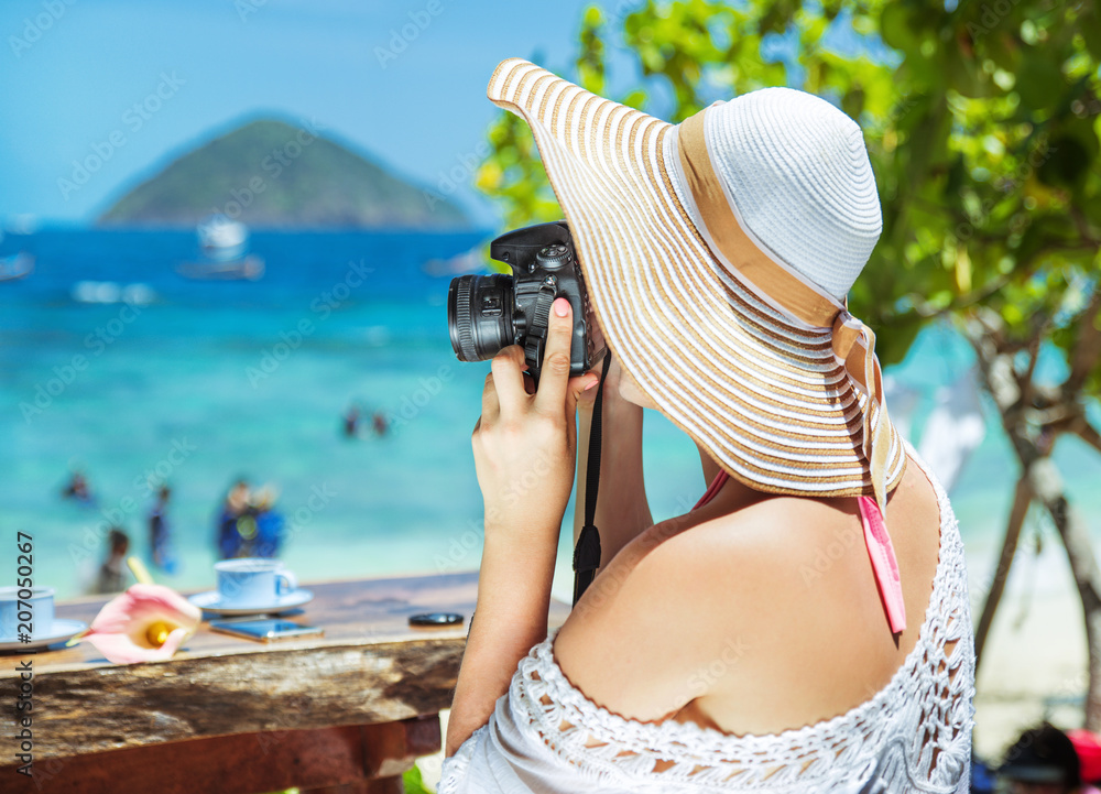 Relaxed, joyful lady taking a photo of a tropical beach