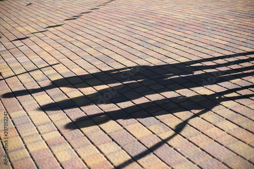 Long shadows of people on the sidewalk tiles in the urban environment at the dawn or dusk