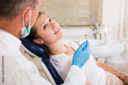 Orthodontist in white is taking examination of an adult patient on the chair