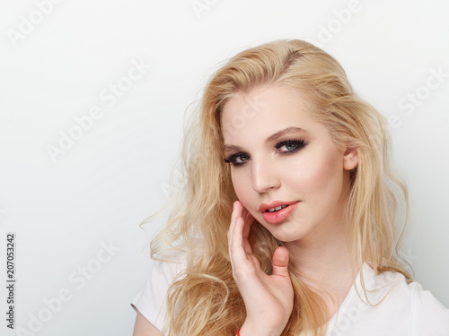 Beauty portrait of model with trendy natural make-up touch chin. Fashion shiny highlighter on skin, sexy gloss lips make-up.