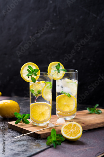 Lemon fruit lime slices caipirinha from Brazil, lemonade mint ice cubes in cold glasses on dark background, alcoholic mojito cockail ice tea green mint leaves, brown sugar spoon, copy space photo