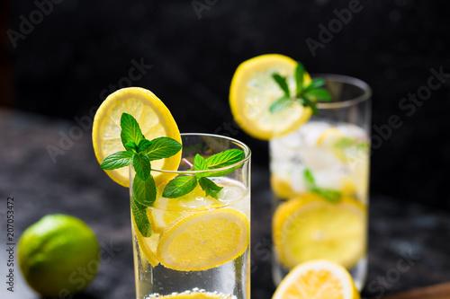 Lemon fruit lime slices caipirinha from Brazil, lemonade mint ice cubes in cold glasses on dark background, alcoholic mojito cockail ice tea green mint leaves, brown sugar spoon, copy space photo