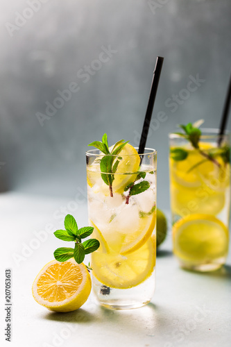 Lemon fruit lime slices caipirinha from Brazil, lemonade mint ice cubes in cold glasses on dark background, alcoholic mojito cockail ice tea green mint leaves, brown sugar spoon, copy space photo