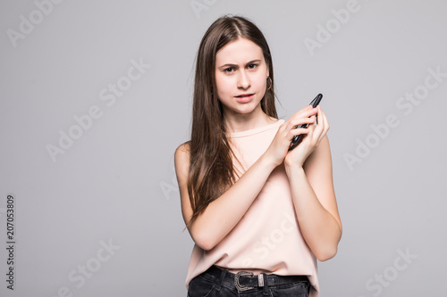 Portrait of a confused asian businesswoman covering mobile phone with palm while talking isolated over white background