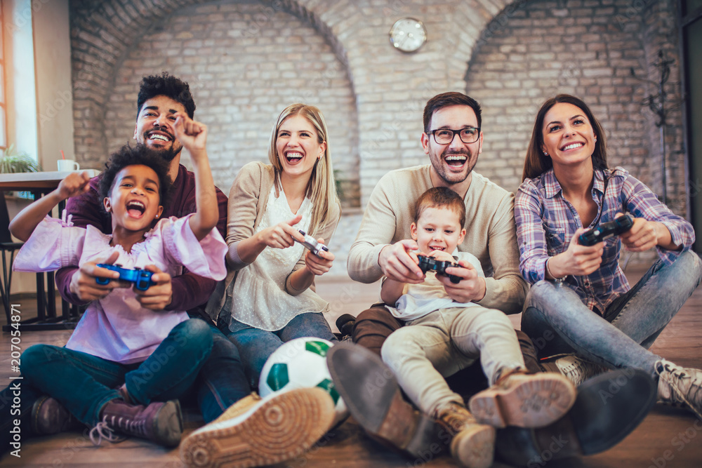Two mixed race couple play video games with their children, having fun. Two mixed race couple play video games with their children, having fun.