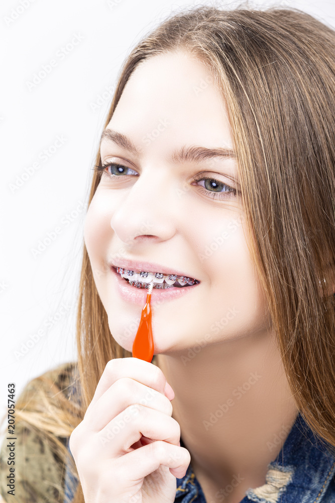 Dental Health Ideas and Concepts.Smiling Caucasian Female Teenager With Teeth Braces. Cleaning Brackets Using Bristle Brush. Dental Health Ideas and Concepts.Smiling Caucasian Female Teenager With Teeth Braces. Cleaning Brackets Using Bristle Brush.