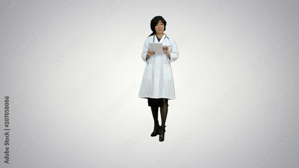 Surgeon woman doctor smile using tablet pc and talking to a camera on white background Surgeon woman doctor smile using tablet pc and talking to a camera on white background