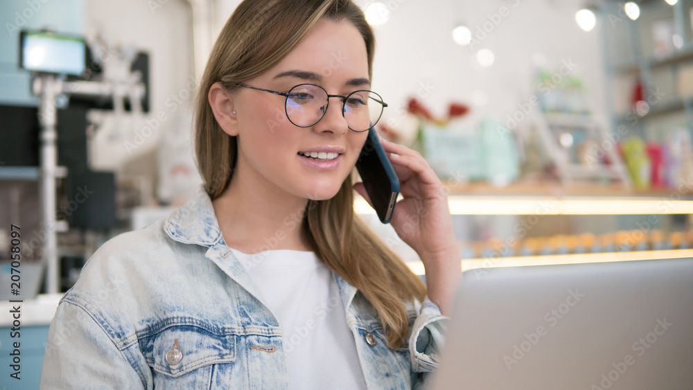 Cute blonde female talking on the phone in modern cafe Cute blonde female talking on the phone in modern cafe