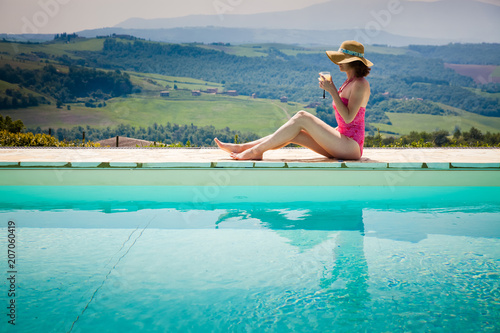 woman sitting by the pool with a cocktail  admiring green ladscape in Tuscany, Italy © Melinda Nagy