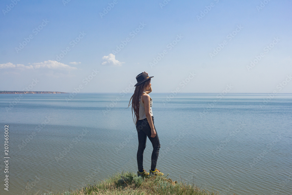 minimalistic landscape with clay cliffs and sea and young woman hiker