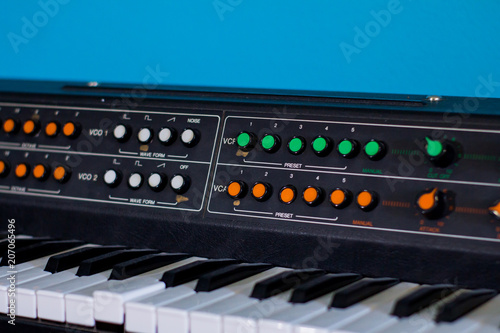 Old synthesizer with colorfull switches on blue background