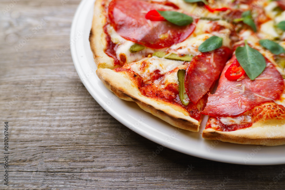 Pizza with salami and gherkins, close up, copy space. Delicious italian cuisine, family restaurant, pizzeria, food recipe, pizza delivery concept