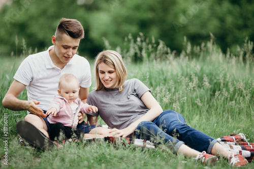 Happy young family enjoy time together outside. Mom, dad and little baby daughter resting in nature. Childhood, parenthood, togetherness, love, happiness concept © Vadym