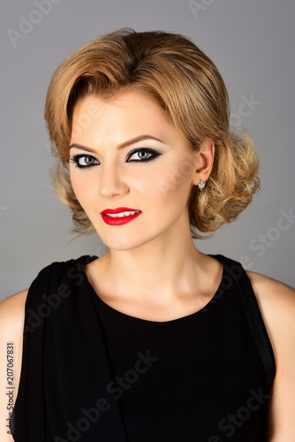 Blonde girl with evening makeup on gray background. Beautiful makeup and black dress. Skin and face care. Jewelry and Beauty. Blonde girl in black evening dress.