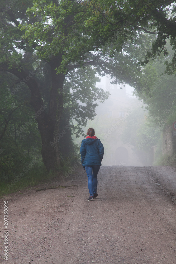 woman walking on misty forest road