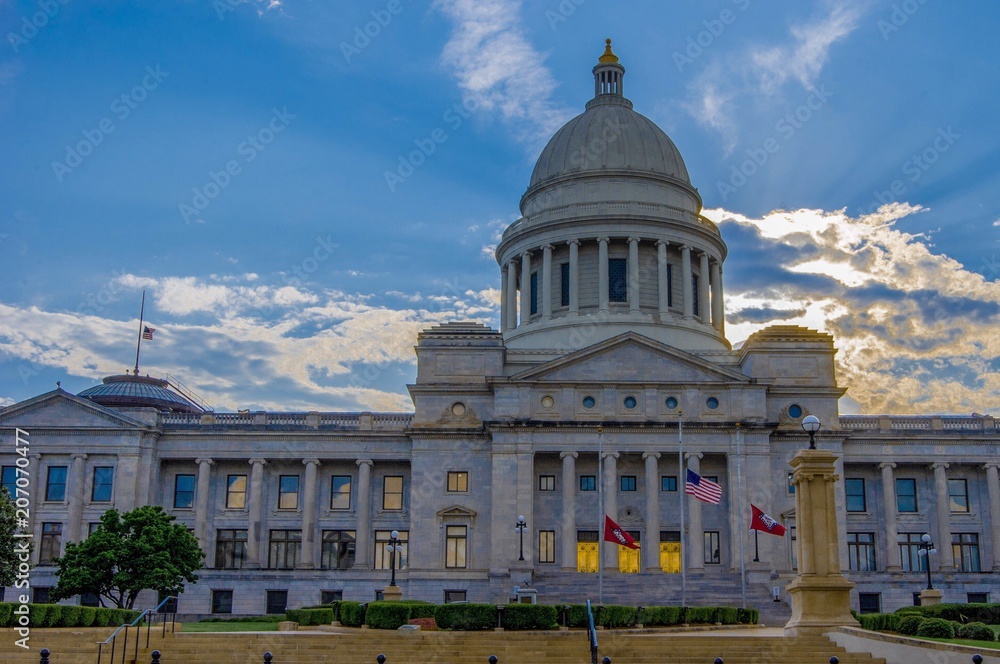 Arkansas state house with sunsetting behind clouds