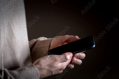 Man's hands using a smartphone on a black background