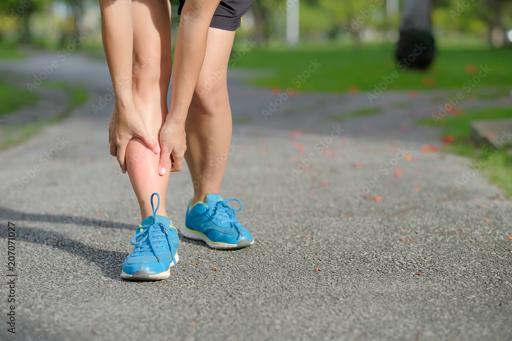 Young fitness woman holding her sports leg injury, muscle painful