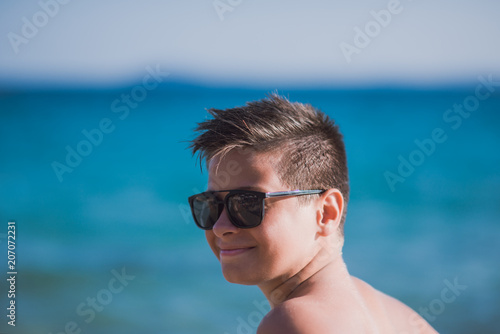 Young kid with sunglasses posing on the beach