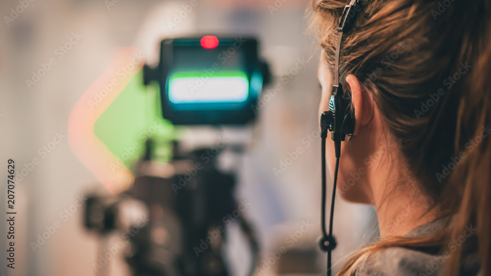 Naklejka premium Behind the scene. Female cameraman shooting film scene with camera