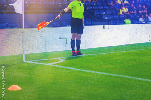 Lineman assistant referee judging and point the flag for corner kick in soccer match.