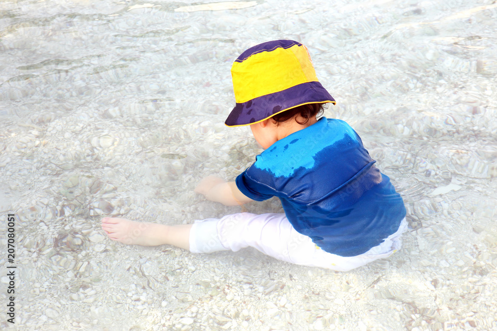 small child sitting in the water in clothes small child sitting in the water in clothes