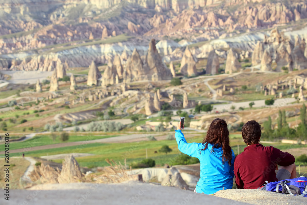 guy and a girl doing a selfie with hills of volcanic rock in the Cappadocia valley, Turkey