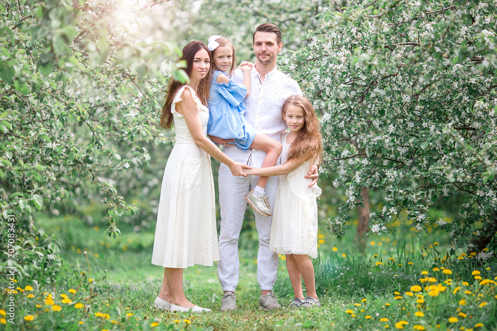 Adorable family in blooming cherry garden on beautiful spring day