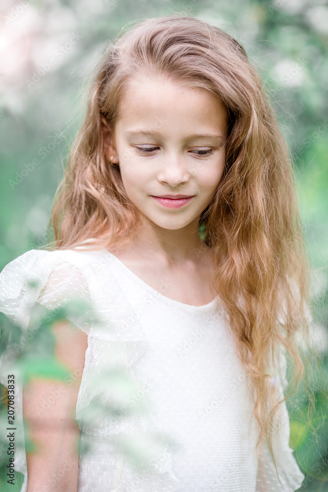 Adorable little girl in blooming apple garden on beautiful spring day Adorable little girl in blooming apple garden on beautiful spring day