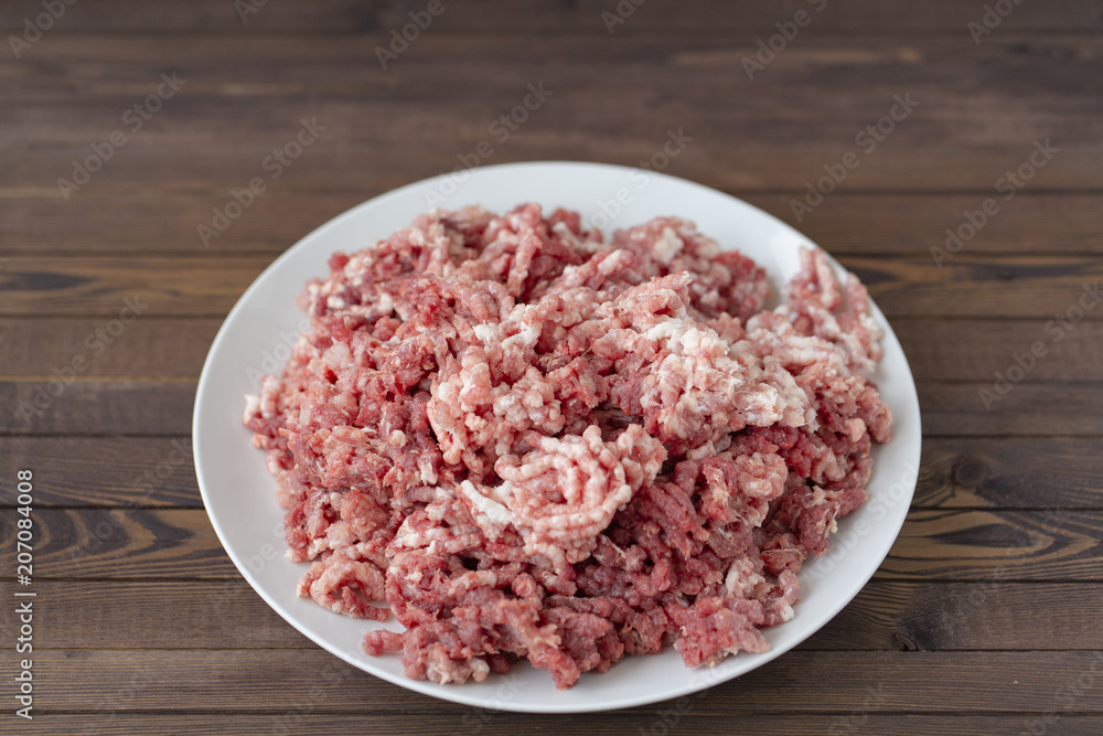 fresh raw minced beef in a plate close up on a rustic wooden table fresh raw minced beef in a plate close up on a rustic wooden table